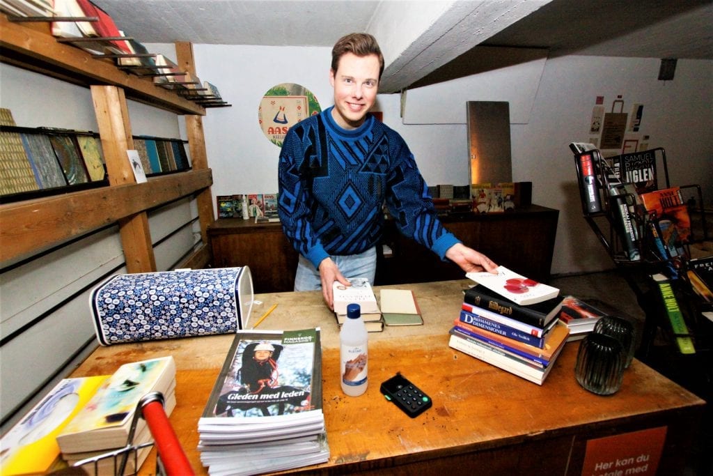 STORTRIVES: Andreas Søvik Helgeberg flyttet tilbake til Svullrya i juni 2019, og sier han stortrives. Her er han bak disken i sitt nyåpnede bokhandleri. Foto: Liv Rønnaug B. Lilleåsen