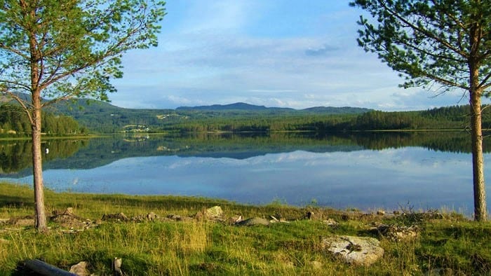 IDYLLISK: Det kan bli meget idyllisk og nasjonalromantisk når en rekke båter går i kortesje på Vermundsjøen på 17.mai - med feststemte mennesker i finstas og med norskeflagg. Foto: Finnskogen.no