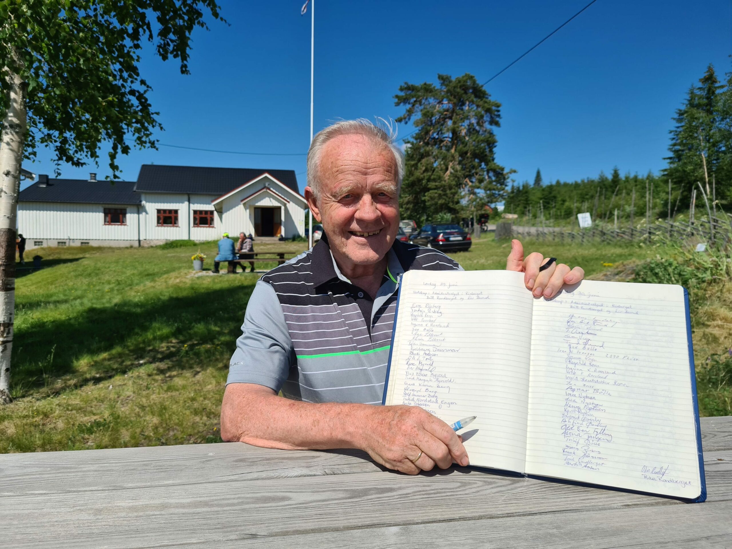HENTER UNDERSKRIFTER: Alle som besøker sommerkafeen i Risberget må skrive seg inn i gjesteboka. Torleif Bølla sørger for at ingen «slipper unna». Sommerkafeen er åpen hver lørdag og søndag gjennom hele skoleferien.