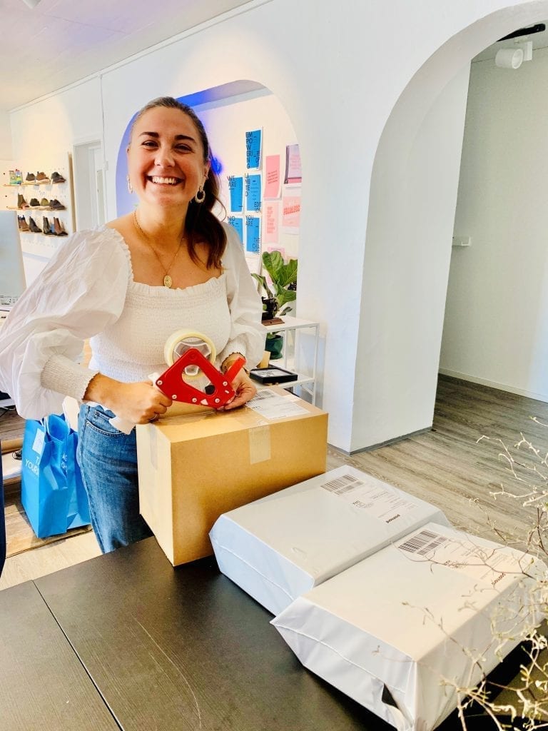 PAKKER: Luisa Arango i Tag your shoes pakker og pakker. Dette er varer som straks skal sendes ut til kunder, og snart kommer sommersandalene. Foto: Liv Rønnaug B. Lilleåsen