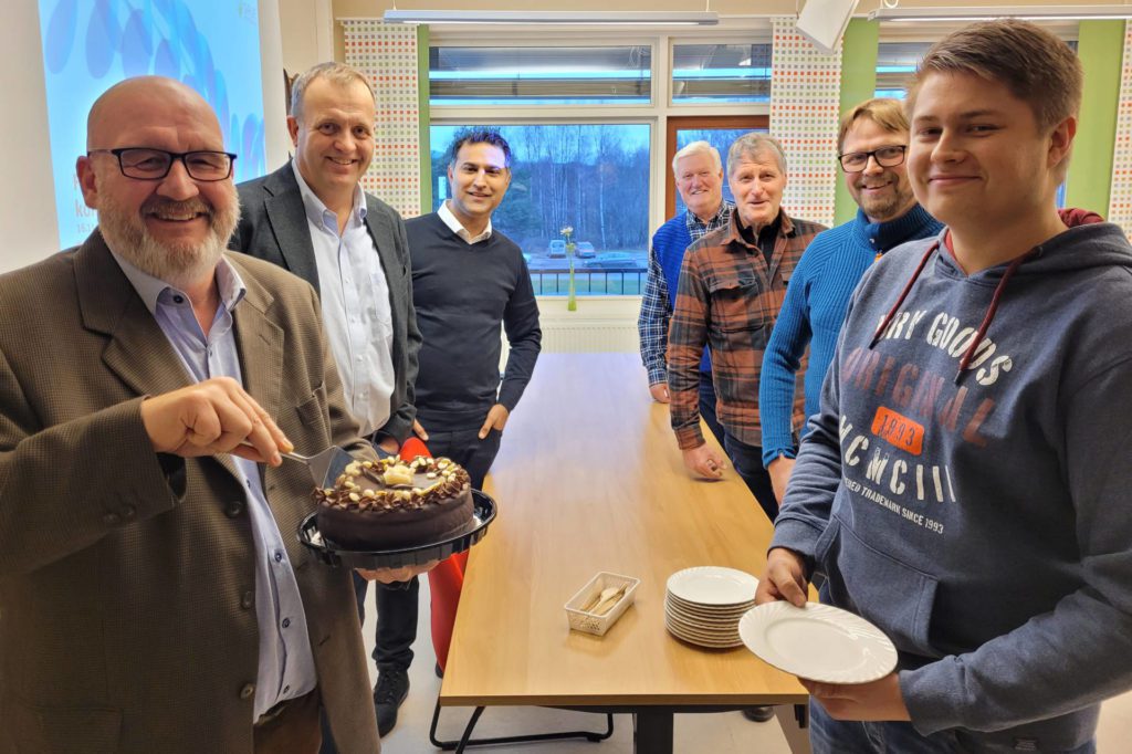 GRUNN TIL Å FEIRE: Med solid økt fiberdekning i Grue er det grunn til å feire. Ordfører Rune Grenberg serverer kake til Cato Bonsak. Videre bak han ser vi Pål Snapa, Gunnar Botilsrud og Ole Einarsrud. Bak Grenberg står moderniseringsdirektør Arne Quist Christensen og prosjektleder Shahzad Aslam fra Telenor.