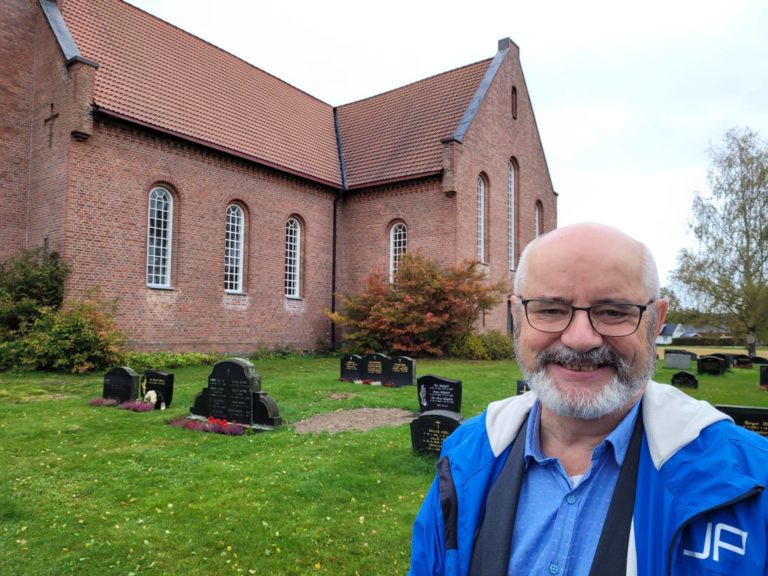 HOLDES ÅPNE: Alle seks kirkene i Åsnes vil ha gudstjenester på julaften, selv om antallet gjester må begrenses. Her står kirkeverge Tord Langmoen utenfor Hof kirke.