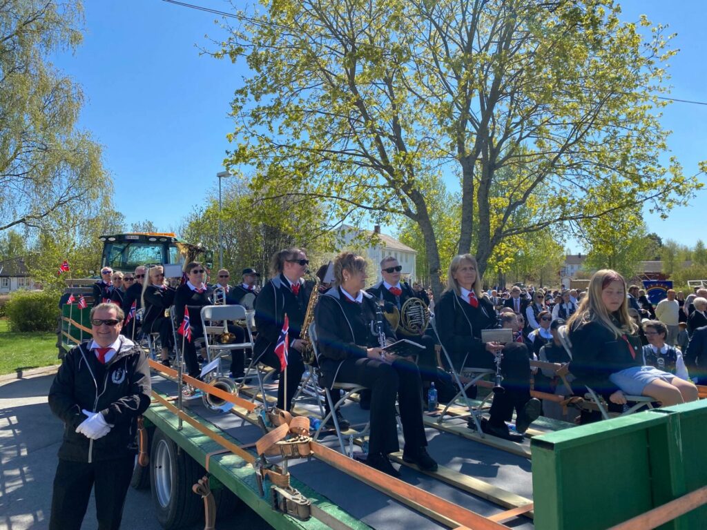 KJØRENDE MUSIKK: Grue Veterankorps hadde en alternativ løsning på marsjeringen i år. De bestemte seg for å sitte på hengeren til en traktor å spille.