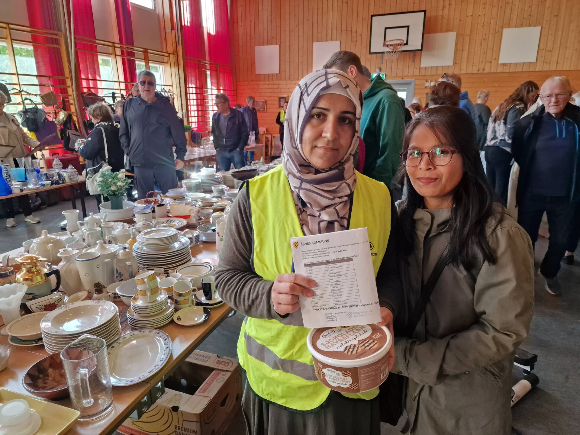 SOLGTE LODD: Badria Nouri (til venstre) og Thongpoon Puangprakhon var travelt opptatt med loddsalg da vi var innom loppemarkedet. Gymsalen var allerede full av folk da.