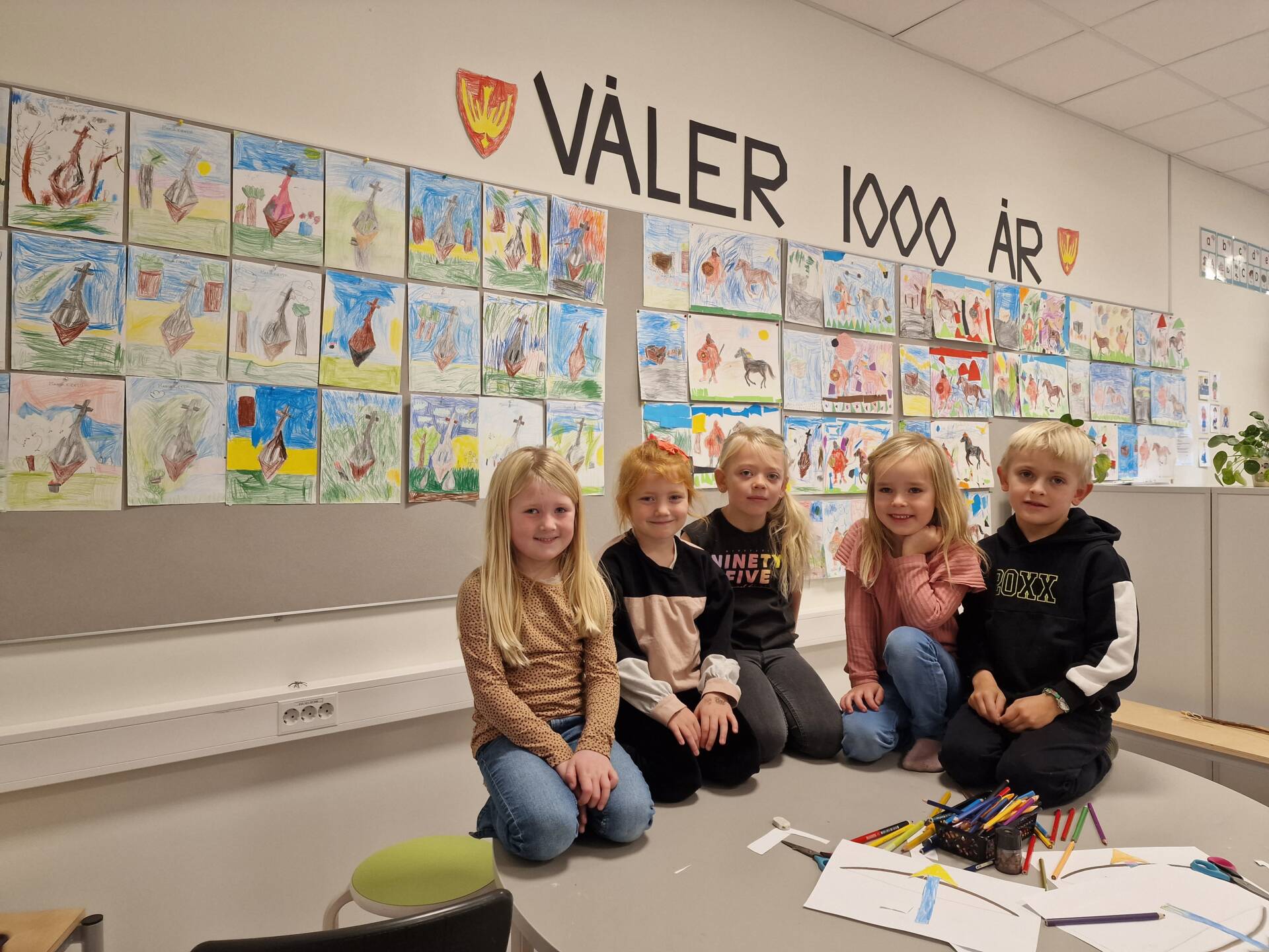 MANGE TEGNINGER: I 1. klasse fikk vi se noen av tegningene som er laget gjennom året. Alma Nilsen (fra venstre), Mina Sofie Olastuen, Lihla Holtmoen, Emine Johnsen og Joel Bronch fikk dispensasjon til å sitte på tegnebordet i anledning dette bildet.